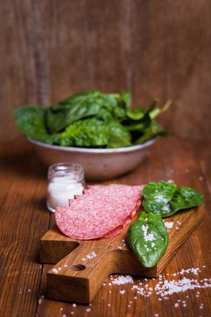 red salami sausage with fresh spinach and large saltの写真素材