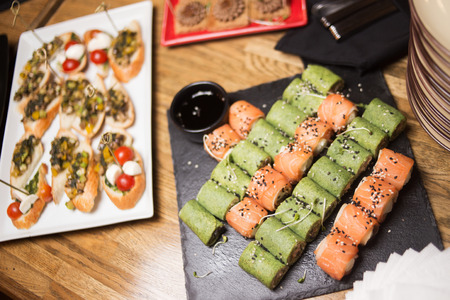 fresh sushi rolls with salmon on white plate in restaurantの写真素材