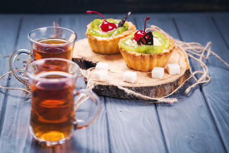 fruit cakes with cream,kiwi,and cherry wit two cup of teaの写真素材