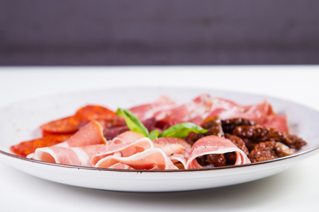 antipasti with ham,sausage and fresh basil isolated on whiteの写真素材