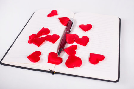 notebook with red pen and hearts isolated on whiteの写真素材