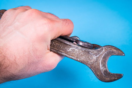 some old rough wrench in hand on blue backgroundの写真素材