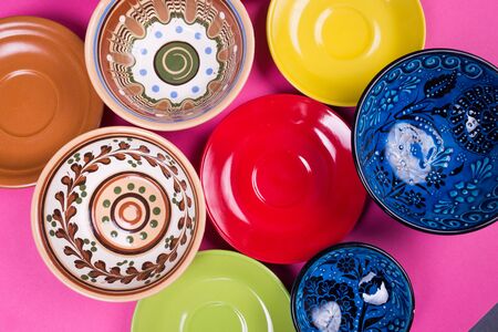 several new colored plates and bowls on a pink surfaceの写真素材