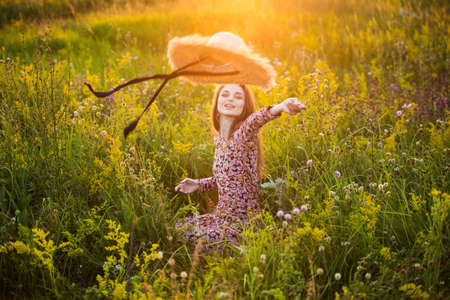 portrait of a beautiful young girl in a hat, outdoors, in the fieldの写真素材