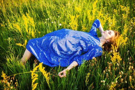 portrait of a beautiful young girl in blue dress, outdoors, in the fieldの写真素材