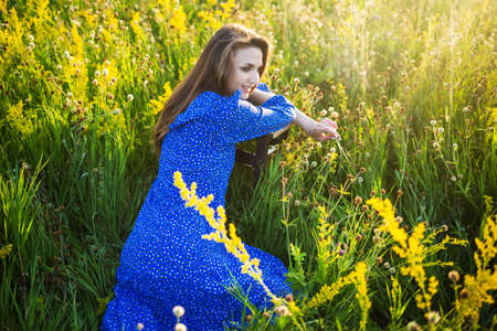 portrait of a beautiful young girl on chair, outdoors, in the fieldの写真素材