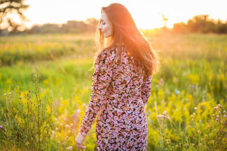 portrait of a beautiful young girl in colored dress, outdoors, in the fieldの写真素材