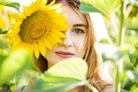 beautiful european girl in a green dress on nature with sunflowersの写真素材
