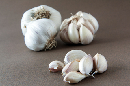 Several heads of garlic with a lot of loose teeth on brown backgroundの写真素材