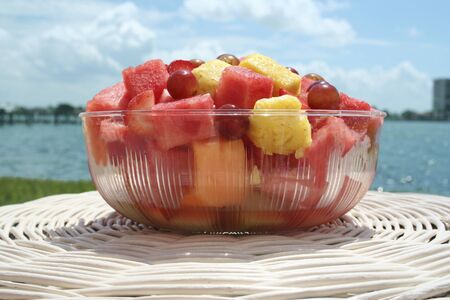 Bowl of fresh fruits on a table in front of the seaside.の写真素材