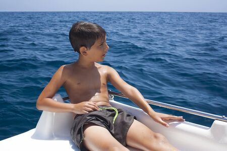 Boy enjoying the promenade on a boat in the calm sea-の写真素材