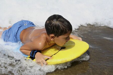 Boy with a yellow board playing in the beach.の写真素材