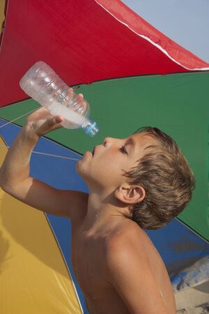 Child trying to drink the last drops of water from a bottle.の写真素材