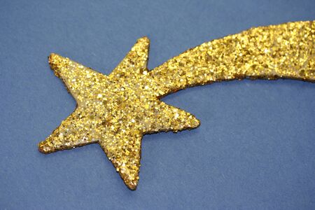 Isolated golden star of Christmas in blue background.の写真素材