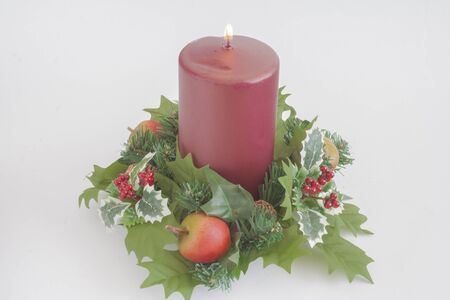 Red lighted candle in the middle of Christmas decorations.の写真素材
