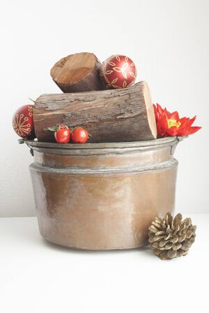 Wood logs in a copper cauldron and Christmas decorations.の写真素材