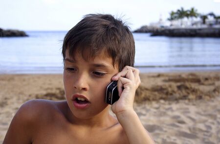 Child talking in the cellular phone in the beach.の写真素材