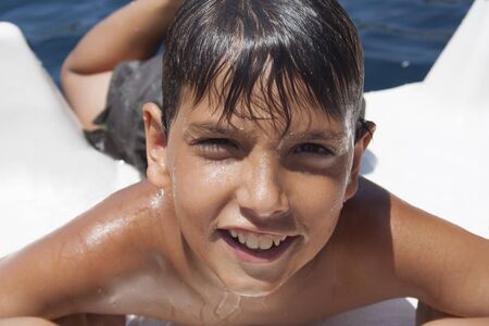 Young boy playing and jumping to the water from a boat.の写真素材