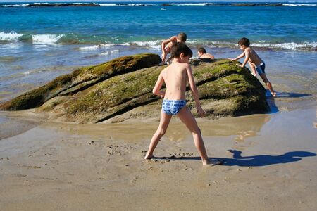Some children playing on a rock in a nice summer day.の写真素材
