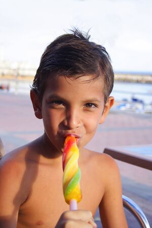 Boy eating a colorful ice cream in the promenade.の写真素材
