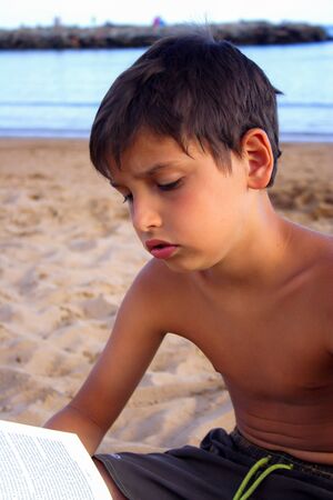 Child in the beach engaged in the reading of a book.の写真素材
