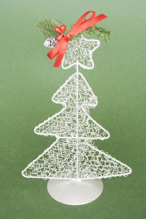 White metallic tree with a red ribbon and green background.の写真素材