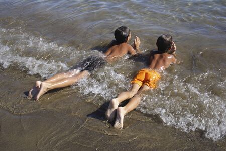 Children enjoying the small waves in the clear water.の写真素材