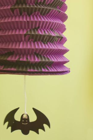 Bat hanging from a colorful halloween lamp.の写真素材