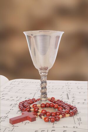 Chalice and rosary on a sheet of religious music.の写真素材