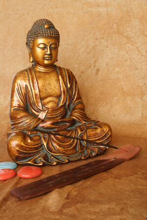 Golden Buddha  and incense stick with holder by the floor.の写真素材