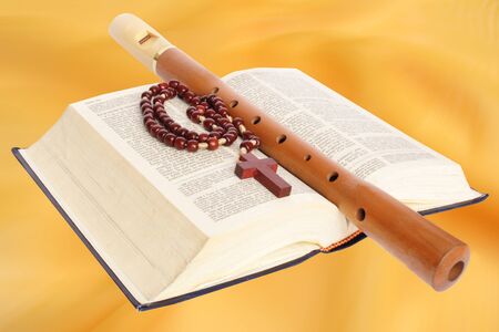 Open bible and rosary with a flute on a yellow background.の写真素材