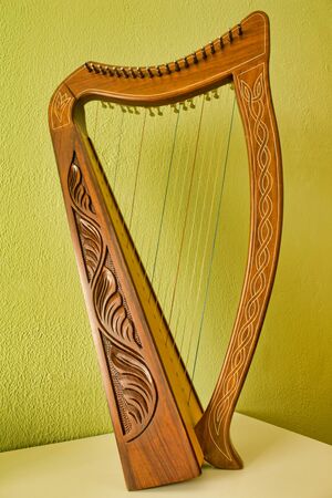 Carved harp on a white table with and green wall behind.の写真素材