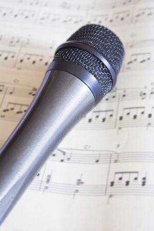 Grey microphone on top of a music sheet.の写真素材