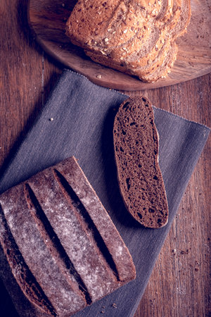 Slices of rye bread on a rustic cutting board and seed bread.
