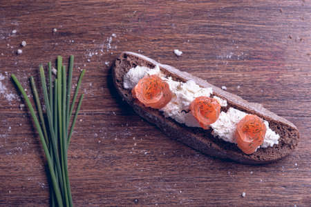 Sandwich with smoked salmon and cottage cheese on a wooden background.の写真素材
