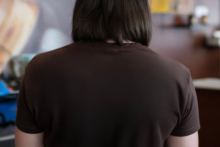 Back of woman with brown t-shirt, short straight hairの写真素材