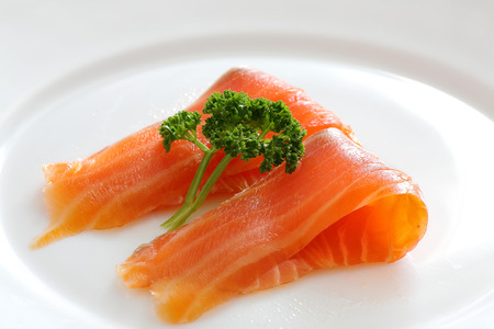 Salmon slices with parsley on a white plate. Close upの写真素材