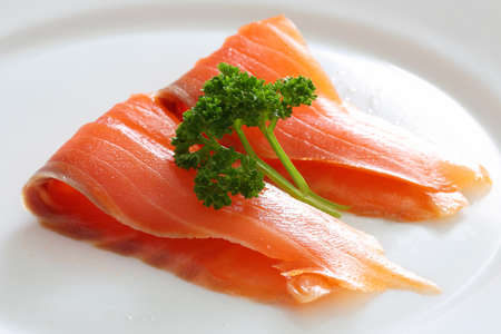 Salmon slices with parsley on a white plate. Close upの写真素材