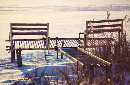 abandoned pier and reeds in winter at sunsetの写真素材