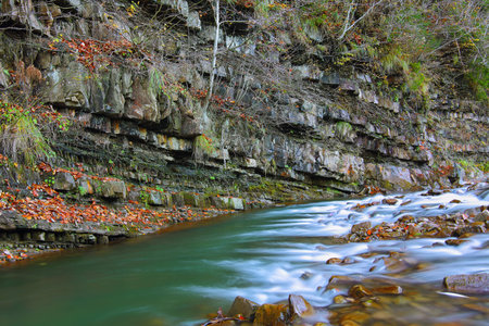 Rocky shore of river in autumn time. Movement of water
