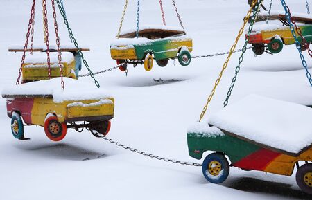 Abandoned carousel in winter time. Empty children playground in winter day. hanging children carsの写真素材