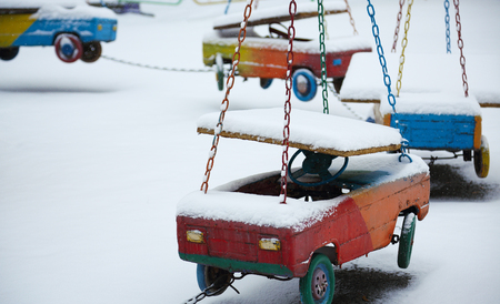 Abandoned carousel in winter time. Empty children playground in winter day. hanging children carsの写真素材