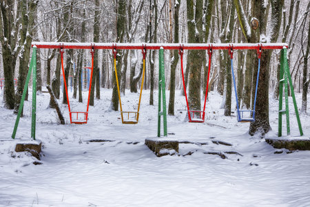 Empty swing in winter time with snow. Children's swing under a thick layer of snowの写真素材