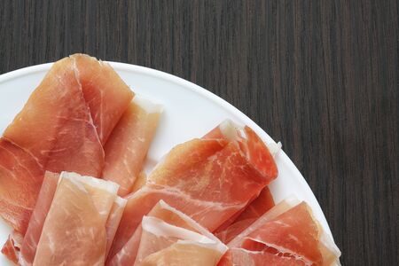 Sliced jamon (hamon) or prosciutto on a wooden background. Selective focusの写真素材