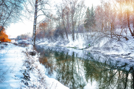 Winter landscape by a river in the sunset. Mirror reflection