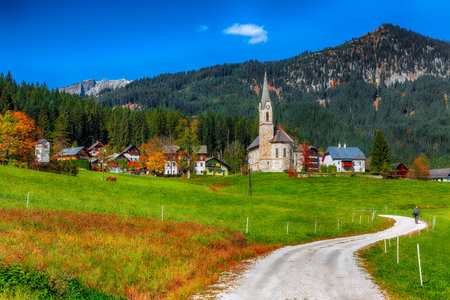 Alpine green fields and traditional wooden houses view of the Gosau village at autumn sunny day....