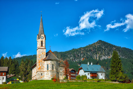 Mountains over Gosau village with Catholic Church under Sunlight. Location: resort village Gosau Salzkammergut region, Gosau Valley in Upper Austria, Alps. Europe.の写真素材