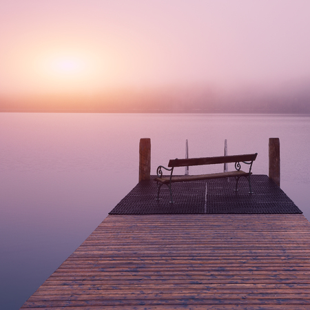 Empty footbridge with a bench on a lake Altausseer at sunrise. Location: resort village Altaussee, Liezen District of Styria, Austria, Alps. Europe.の写真素材