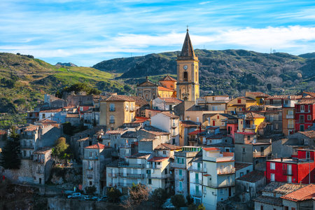 Panorama of the belltower and the village in the valley at sunrise. Mountain village Novara di Sicilia, Sicily, Italyの写真素材