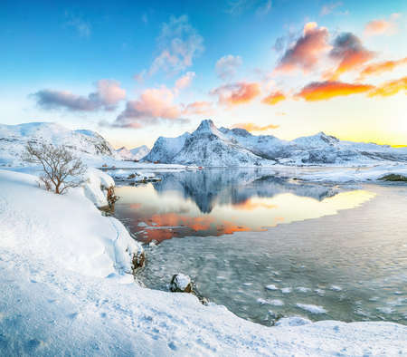 Fantastic frozen Flakstadpollen and Boosen fjords and reflection in water during sunrise with Hustinden mountain on background. Location: Flakstadoya island, Lofoten; Norway, Europeの写真素材